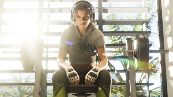 Lucia Caminos assise sur un banc de musculation, casque audio sur les oreilles